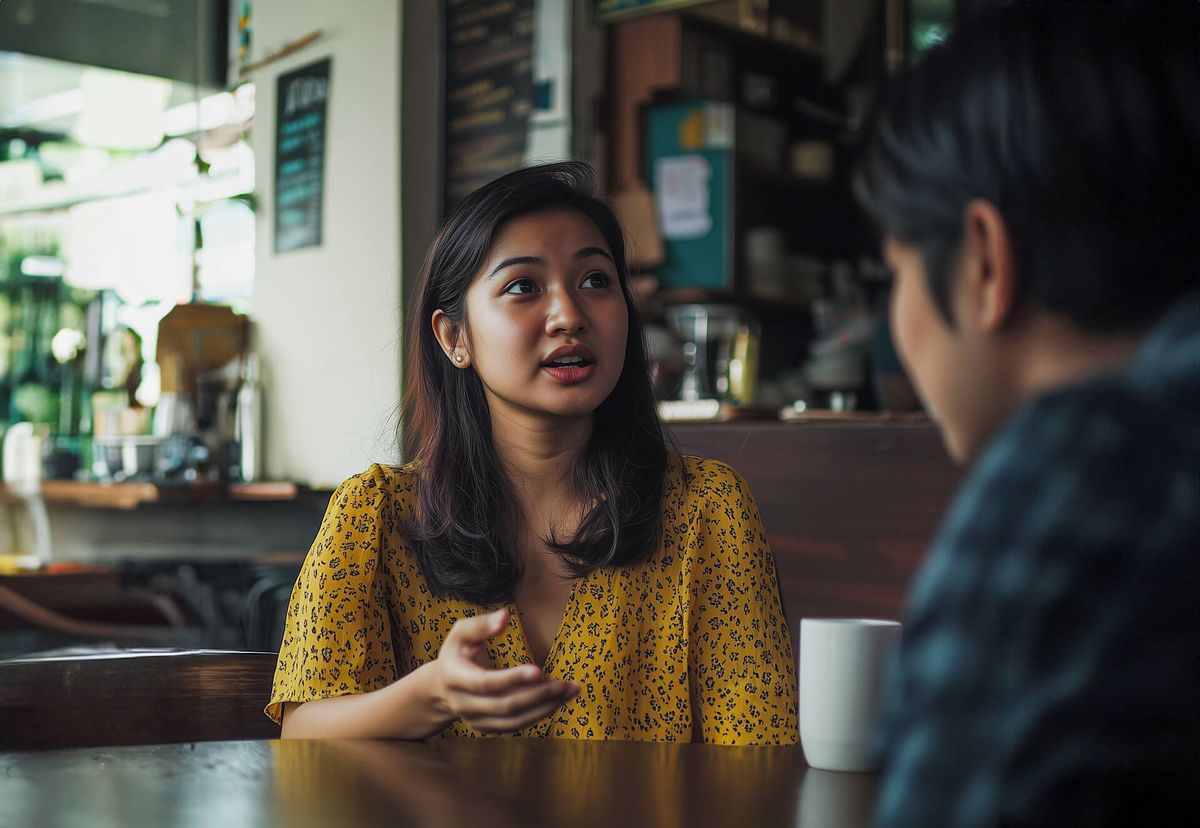 A woman explaining a document to a man in a cafe setting.